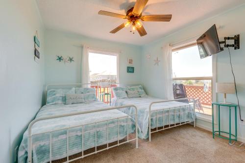 two beds in a room with a ceiling fan at Breezy Dauphin Island Vacation Rental with Deck! in Dauphin Island