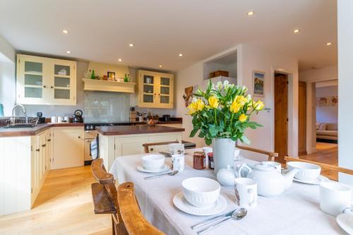 Una cocina con una mesa con un jarrón de flores encima. en Peach Cottage, en Poulton