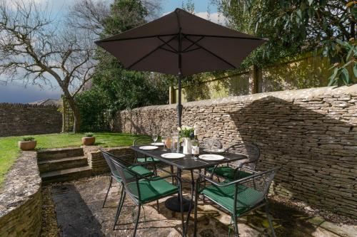 Poulton的住宿－Peach Cottage，花园内桌椅和遮阳伞
