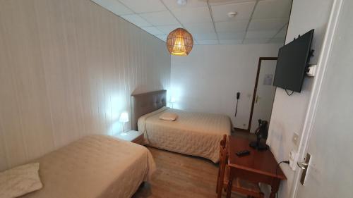 Cette petite chambre comprend deux lits et une télévision. dans l'établissement Hôtel du Roc, à Castellane