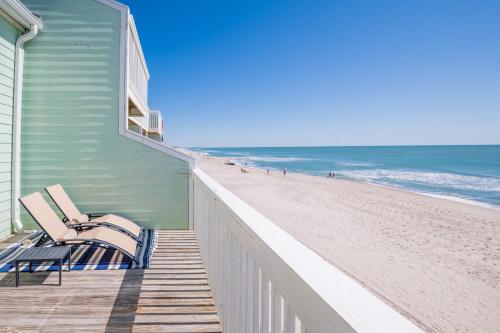 a deck with two chairs on the beach at Oceanfront Condo with 3+ Pools - Ocean Dunes 1507 in Kure Beach