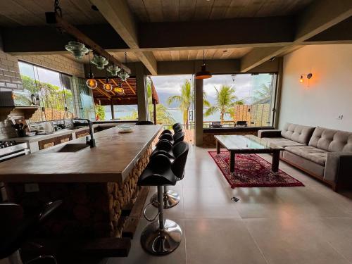 uma cozinha com um bar com cadeiras e um sofá em Linda casa em condomínio fechado com vista para Ilha das Cabras em Ilhabela