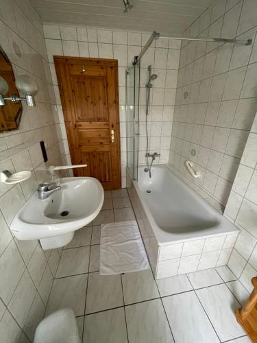 uma casa de banho com um lavatório, uma banheira, um WC e um lavatório. em Ferienwohnung zum Nürburgring em Münk