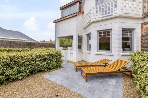 two benches on a patio in front of a house at Maison Lucie in Koksijde