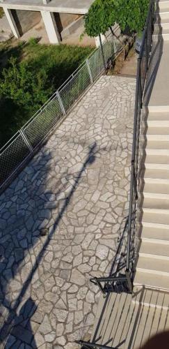 a shadow of a fence on a stone walkway at Apartmani Pilica in Ravanj