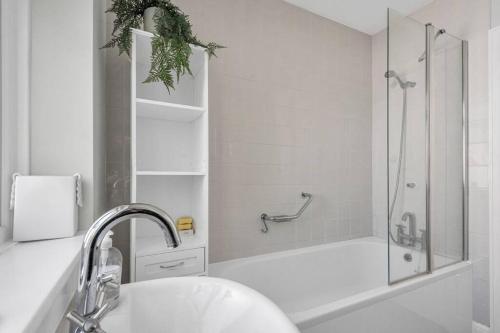 baño blanco con ducha y lavamanos en Pass the Keys Little Haven A stunning Bungalow in Minnis Bay, en Birchington