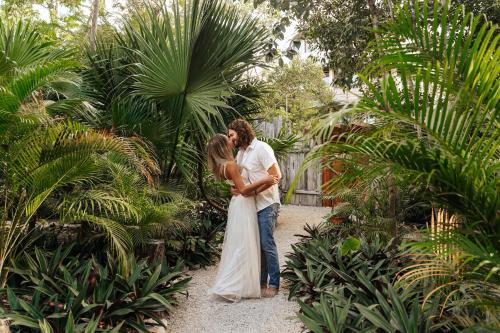 Una novia y un novio besándose en un jardín en Nahouse Jungle Lodges en Tulum