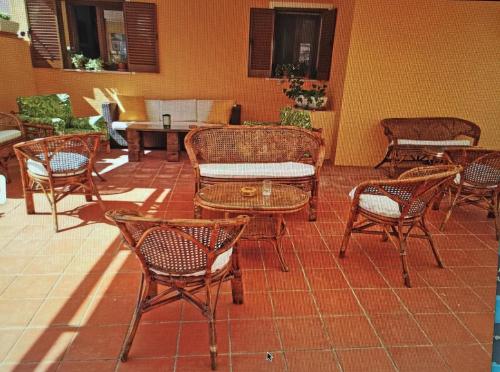 a patio with wicker chairs and tables on a tile floor at LE CAMERE SUL PORTO in Palau