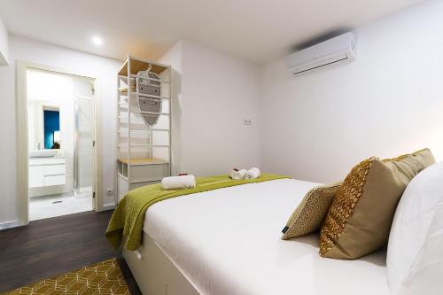 ein Schlafzimmer mit einem großen weißen Bett mit gelber Bettwäsche in der Unterkunft Benfica Apartments I by Homing in Lissabon