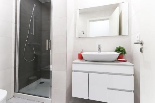 La salle de bains blanche est pourvue d'un lavabo et d'une douche. dans l'établissement Benfica Apartments III by Homing, à Lisbonne