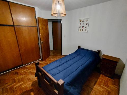 1 dormitorio con 1 cama azul y armario de madera en Departamento Nueva Cordoba en Córdoba
