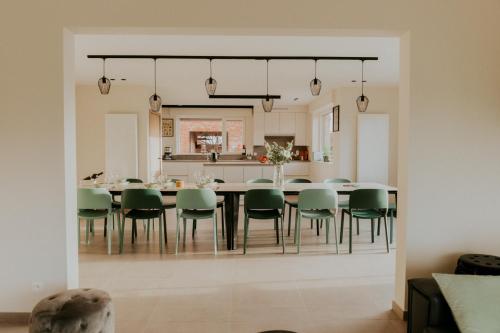 a dining room with a table and green chairs at Luxe Vakantiewoning De Veldhoek in Wingene