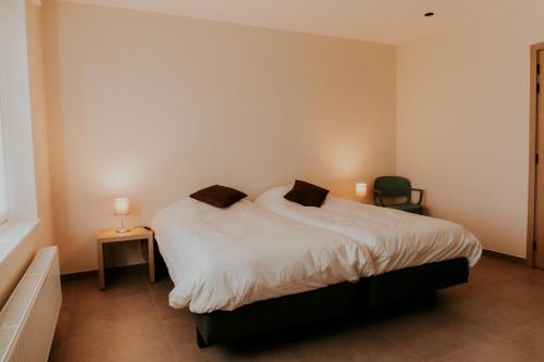 a bedroom with a large white bed with a chair at Luxe Vakantiewoning De Veldhoek in Wingene