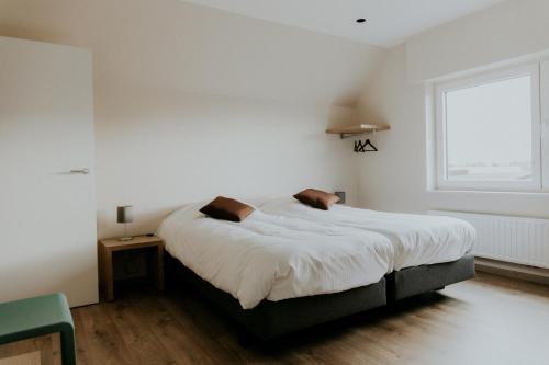 a bedroom with a bed with white sheets and a window at Luxe Vakantiewoning De Veldhoek in Wingene