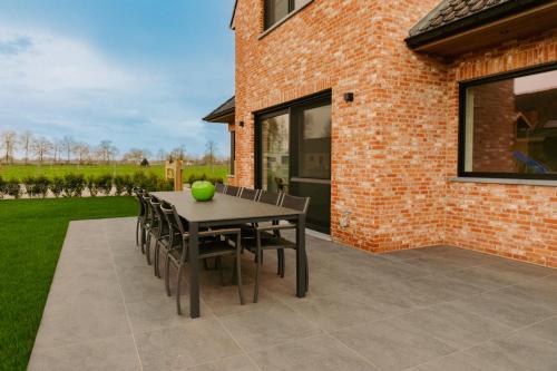 a patio with a table and chairs and a brick building at Luxe Vakantiewoning De Veldhoek in Wingene