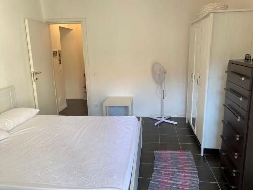 Schlafzimmer mit einem weißen Bett und einem Bodenventilator in der Unterkunft Appartamento - Il Rustico in Manerba del Garda