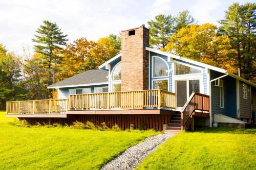 a home with a wrap around porch and a chimney at Point Sebago Resort in Casco