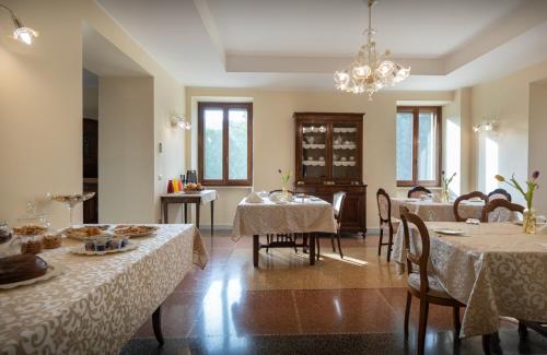 ein Esszimmer mit Tischen, Stühlen und einem Kronleuchter in der Unterkunft Agriturismo Villa Val D'Olivi in Capodacqua