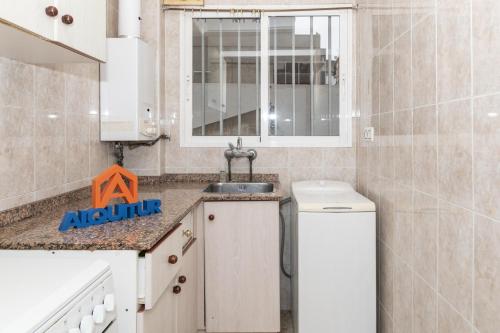 eine kleine Küche mit einem Waschbecken und einem Spiegel in der Unterkunft Estirpe, 2º-4 in Cullera