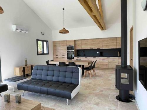 un salon avec un canapé bleu et une cuisine dans l'établissement villa 8Pers au calme avec superbe vue barbecue wifi, à La Panouse