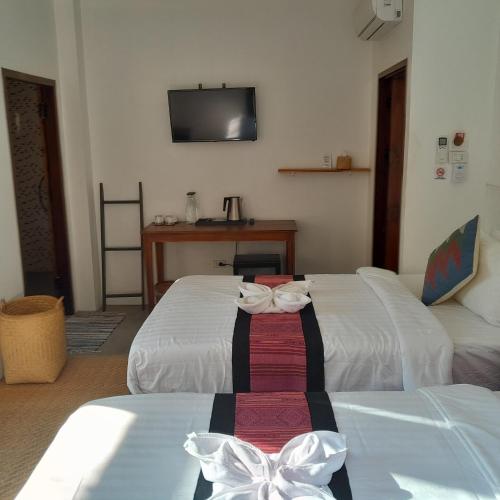 a room with three beds with a tv on the wall at Moonlight Champa Riverview in Luang Prabang