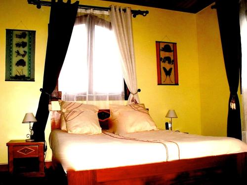 a bedroom with a bed with a window and two lamps at Iarimbato Hotel in Antananarivo
