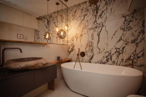 a bathroom with a large white tub and a marble wall at The Luxury Garden Apartment in Shkodër