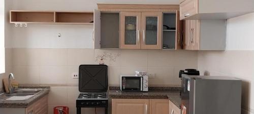 a small kitchen with a stove and a microwave at Selah Holiday Apartment at Sebuleni Nyali in Mombasa