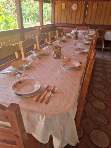 una mesa larga con platos y cubiertos en Casa Delia, en Sulina