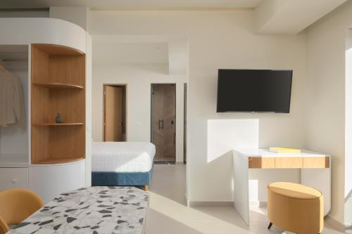 a room with a bed and a desk and a tv at Ostria Deluxe Suite Studio in Rethymno Town