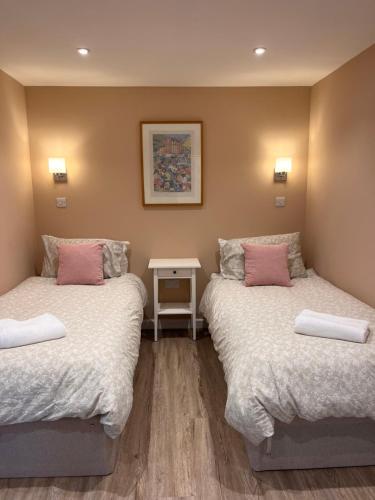 two beds with pink pillows in a room at The Piggery in Chichester