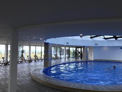 a large swimming pool in a building with chairs at Orbi City Hotel Group Batumi in Batumi