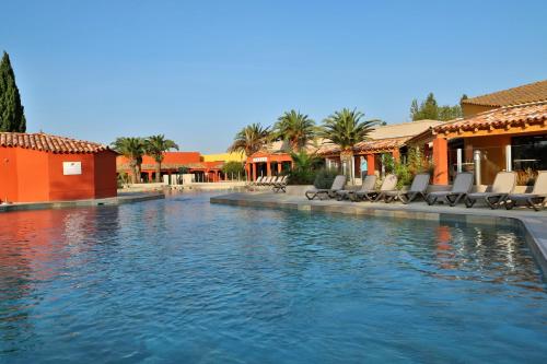 - une piscine dans un complexe avec des chaises et des bâtiments dans l'établissement SOWELL HOTELS L'Olivier, à Arles