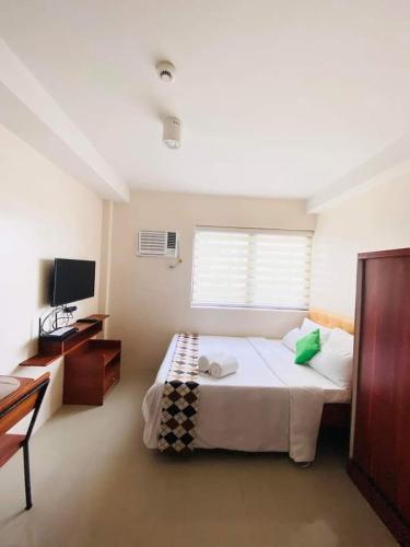 een slaapkamer met een groot bed en een televisie bij Persimmon Condominium Cebu City in Cebu City