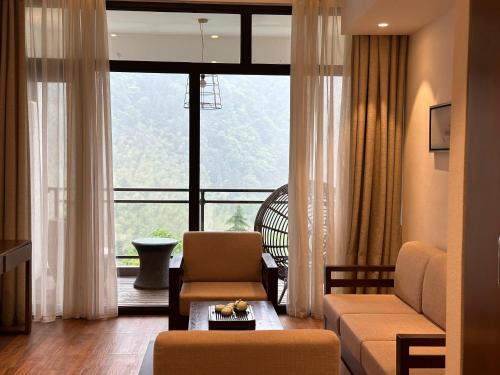 a living room with a couch and a large window at Zhangjiajie National Park Nvue Resorts in Zhangjiajie