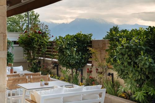 a patio with tables and chairs and mountains in the background at ELLE Rooms & Suites in Paralia Katerinis