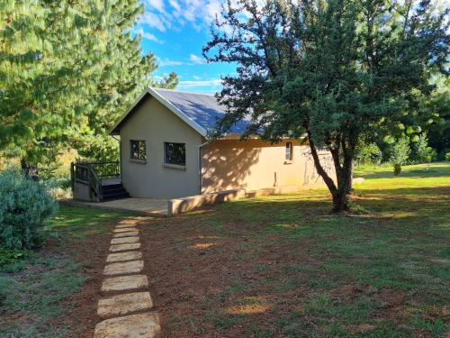 a small white house with a tree and a walkway at Ukutula Resort in Dullstroom