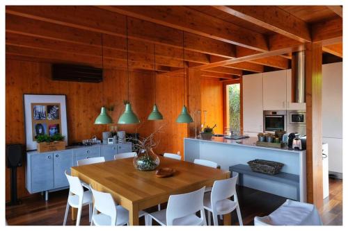 uma cozinha com uma mesa de madeira e cadeiras brancas em Gêres! Caniçada House! em Gerês