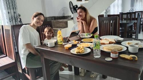 twee vrouwen en een baby zittend aan een tafel met eten bij Ceylan Star Guest Inn in Wellawaya