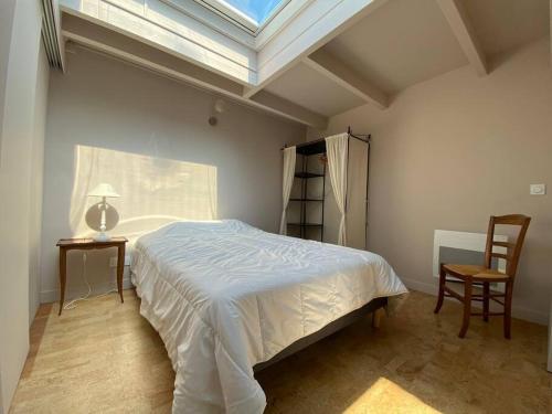 una camera da letto con un letto, una finestra e una sedia di Dépendance complète centre-ville de La Teste a La Teste-de-Buch