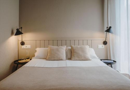 - une chambre dotée d'un grand lit avec des draps et des oreillers blancs dans l'établissement Hotel Llane Petit, à Cadaqués