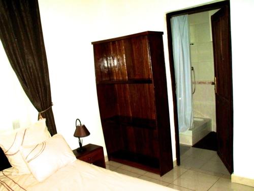 a bedroom with a bed and a bathroom with a shower at Iarimbato Hotel in Antananarivo