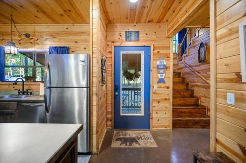 a kitchen with a refrigerator and wooden walls at Hickory Bear - Cabin surrounded by pines, Sleeps 10, Hot Tub, Fire Pit, Arcade, Foosball Table & Deck Slide in Broken Bow