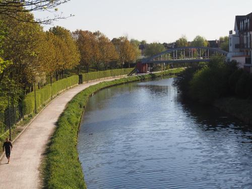 a man walking along a path next to a river at Hotel Du Croisé in Marcq-en-Baroeul
