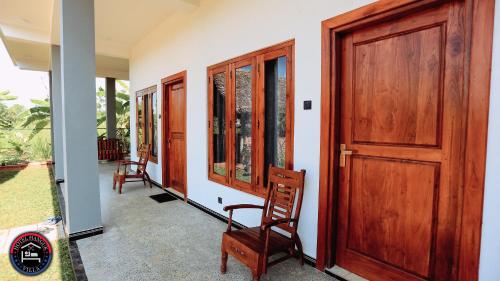 porche con puerta de madera y 2 sillas en Hotel Hanguk Villa en Dambulla