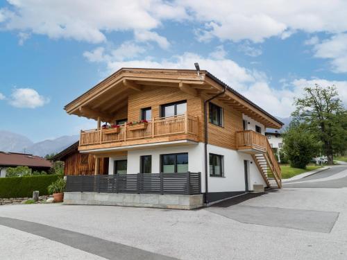 ein Haus mit einem Holzdach und einem Balkon in der Unterkunft Hotel Baumgarten & Chalet Baumgarten in Angerberg