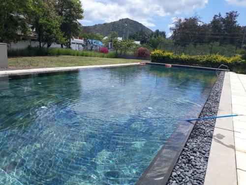 a swimming pool with blue water in a yard at 2 bedrooms charming apartment, West Island Resort in Rivière Noire