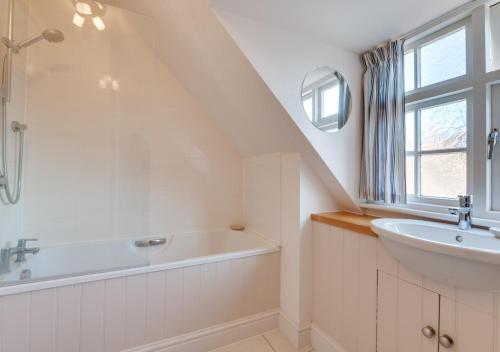 a white bathroom with a sink and a bath tub at 4 Dormy House in Brancaster