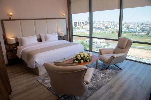 ein Hotelzimmer mit einem Bett und zwei Stühlen in der Unterkunft Jeddah Homes Boutique Hotel in Amman