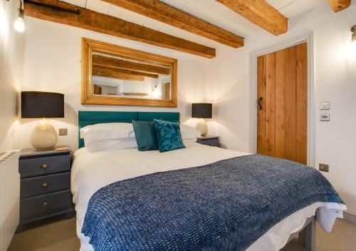 een slaapkamer met een blauw en wit bed en een spiegel bij 72 Starboard in Wells next the Sea